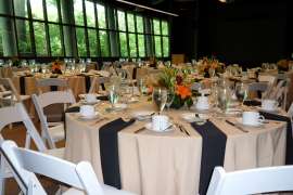 Numerous well-set tables in a room with a wall of windows.