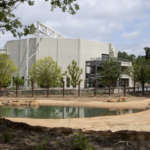 A view across the elephant exhibit's pond to the large, white structure of Savanna Hall.