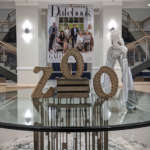 A table in the foyer of Savanna Hall decorated with letters that spell Zoo. In the background is a large print out of the cover of an issue of Modern Luxury Datebook and a stilted acrobat in a zebra costume.