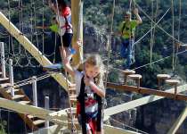 Three children navigate an outdoor ropes course.