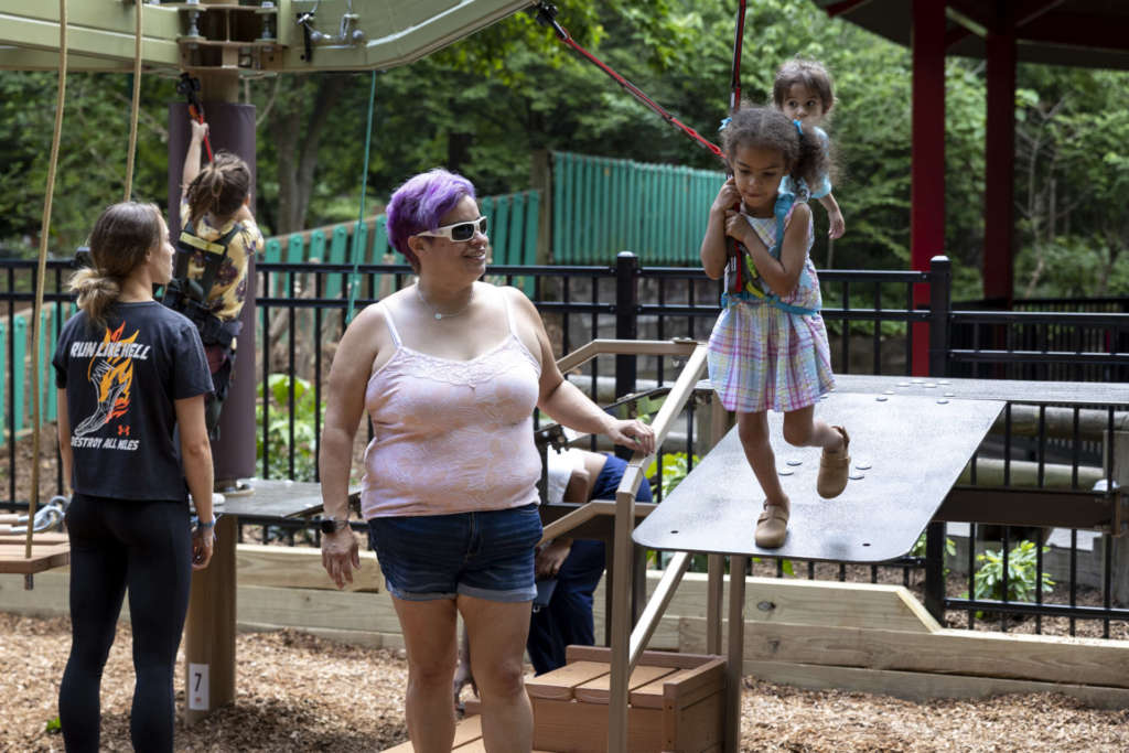 A small child prepares to jump off the ramp for the zipline feature of Treetop Tykes Trail, a new aerial ropes course for children.