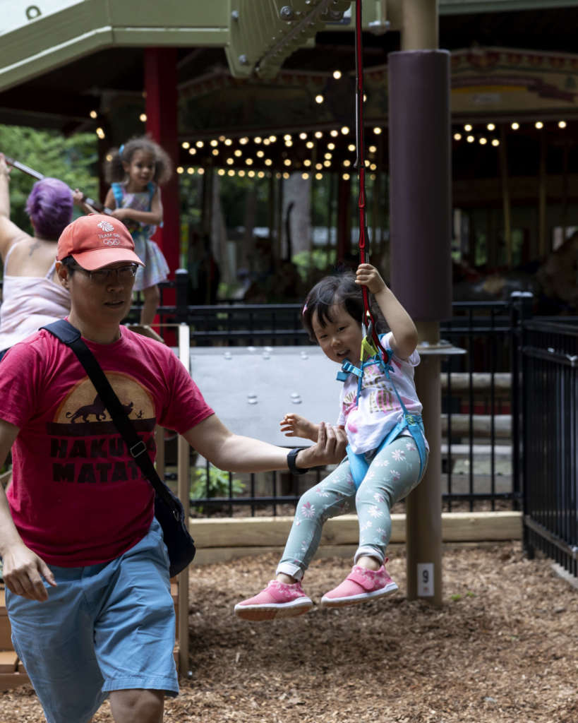 A small child prepares to jump off the ramp for the zipline feature of Treetop Tykes Trail, a new aerial ropes course for children.